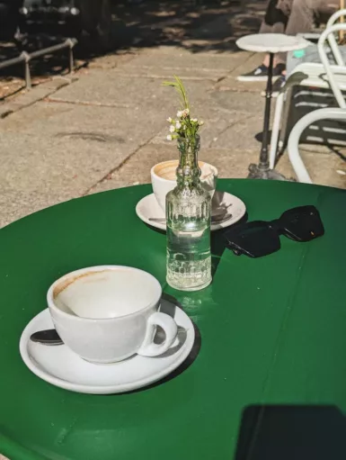 a cup of coffee and a vase of flowers on a table