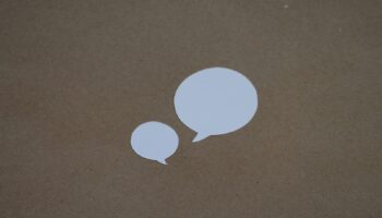 two white speech bubbles sitting on top of a brown surface