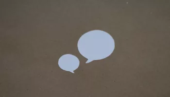two white speech bubbles sitting on top of a brown surface