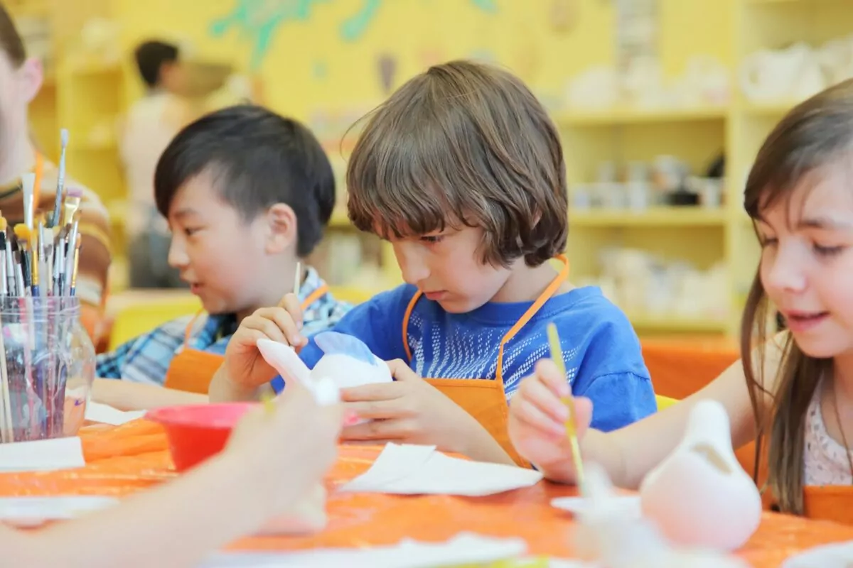 Children painting ceramic figures in an art class